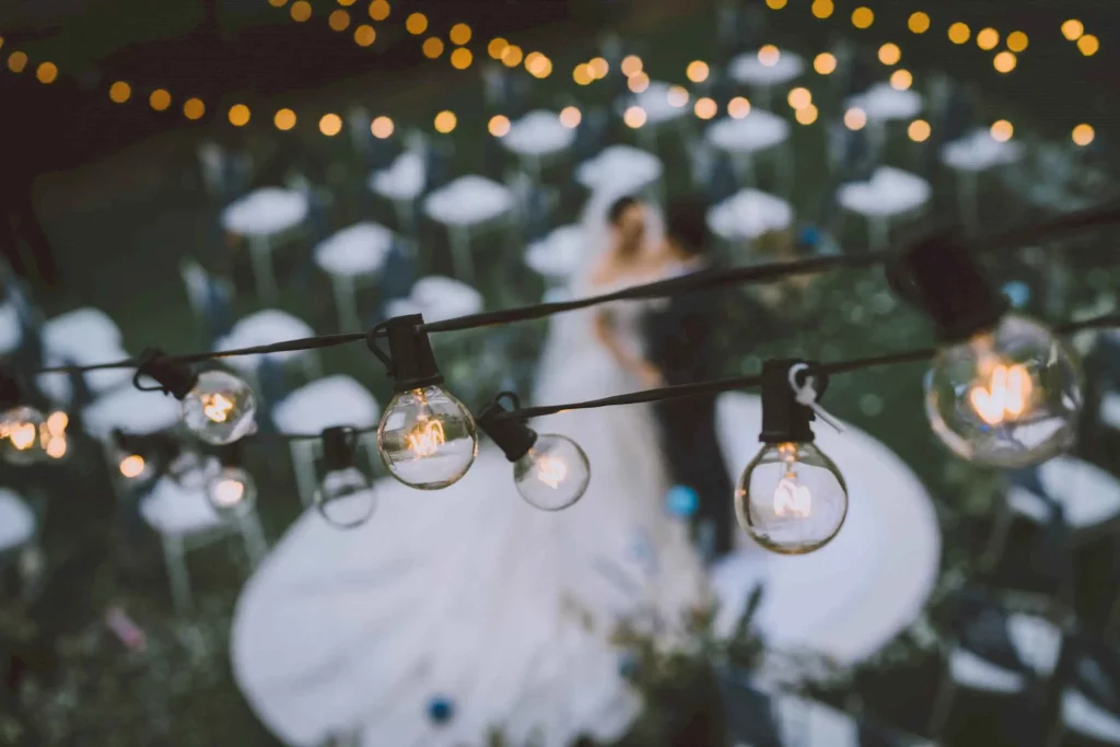 beautiful wedding photo of string lights with bride and groom in the background